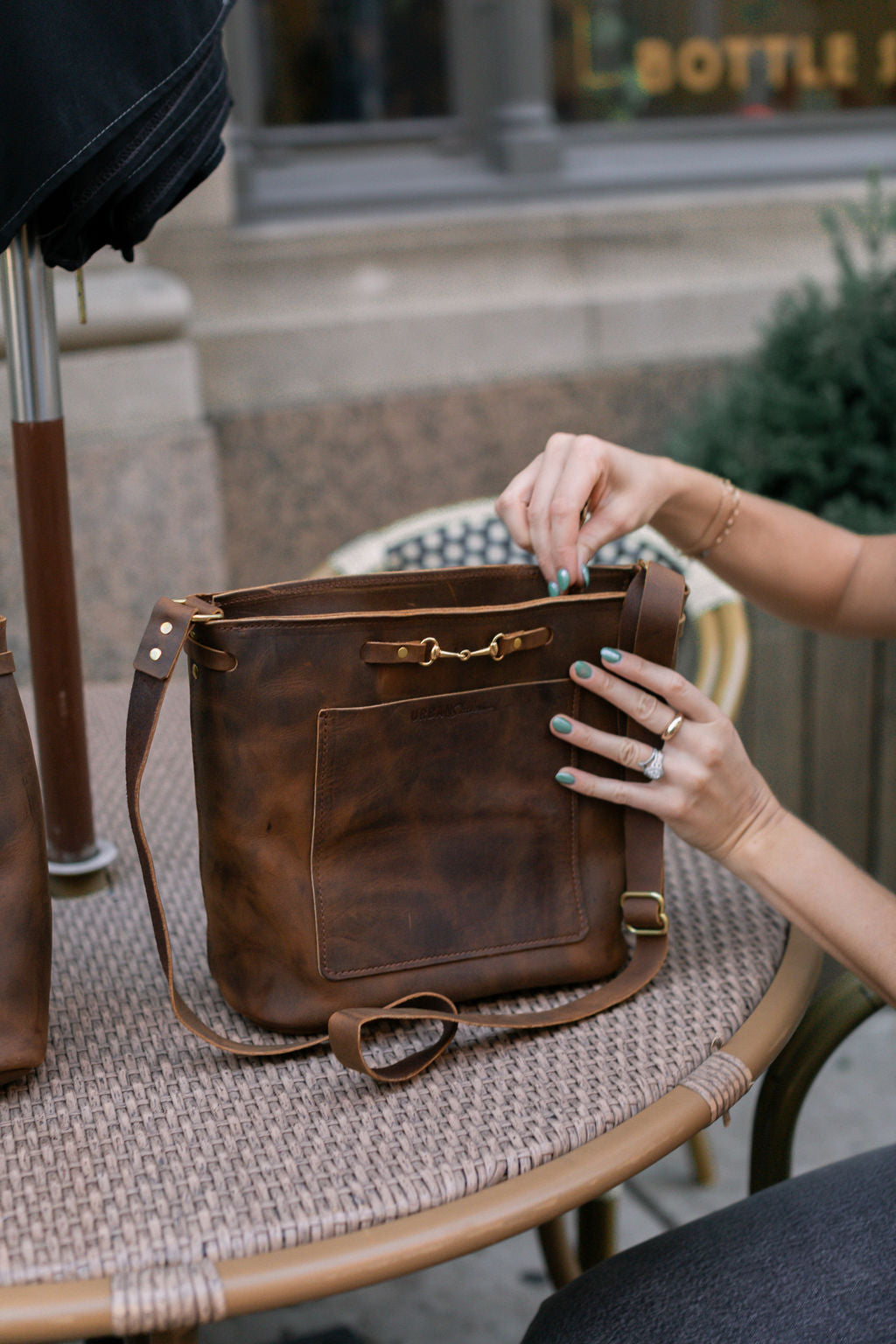 A woman unzips a rustic brown Lexington Julep that is sitting on a table.