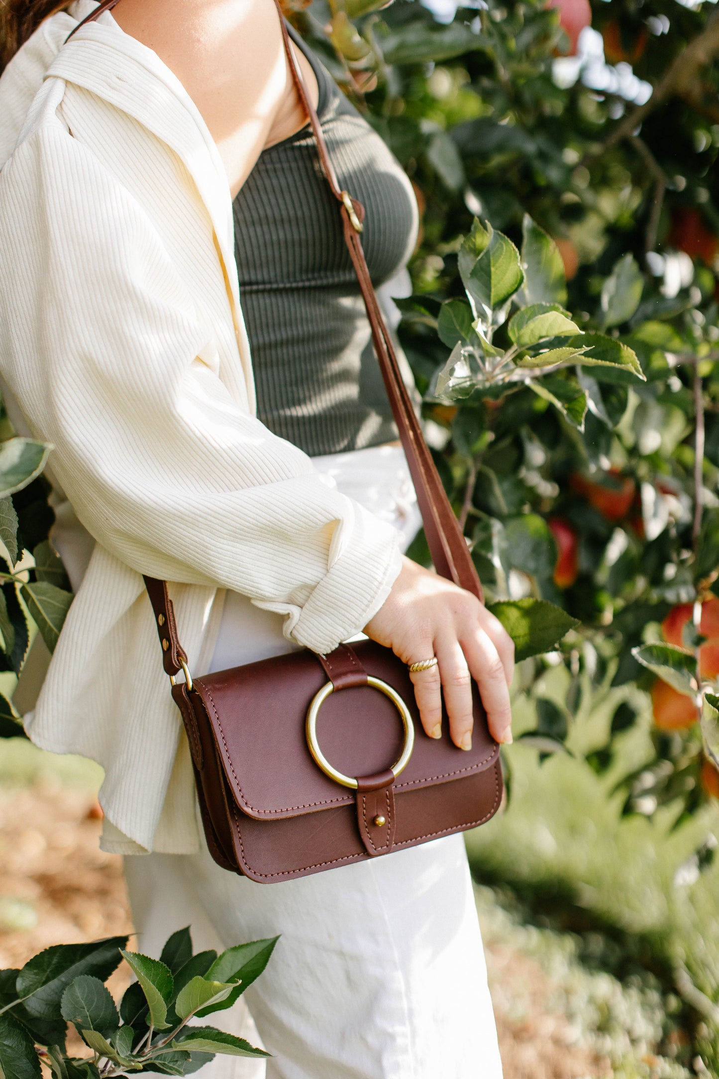 A woman carries the 5-pocket Crossbody Bag in Chestnut Brown over her shoulder.