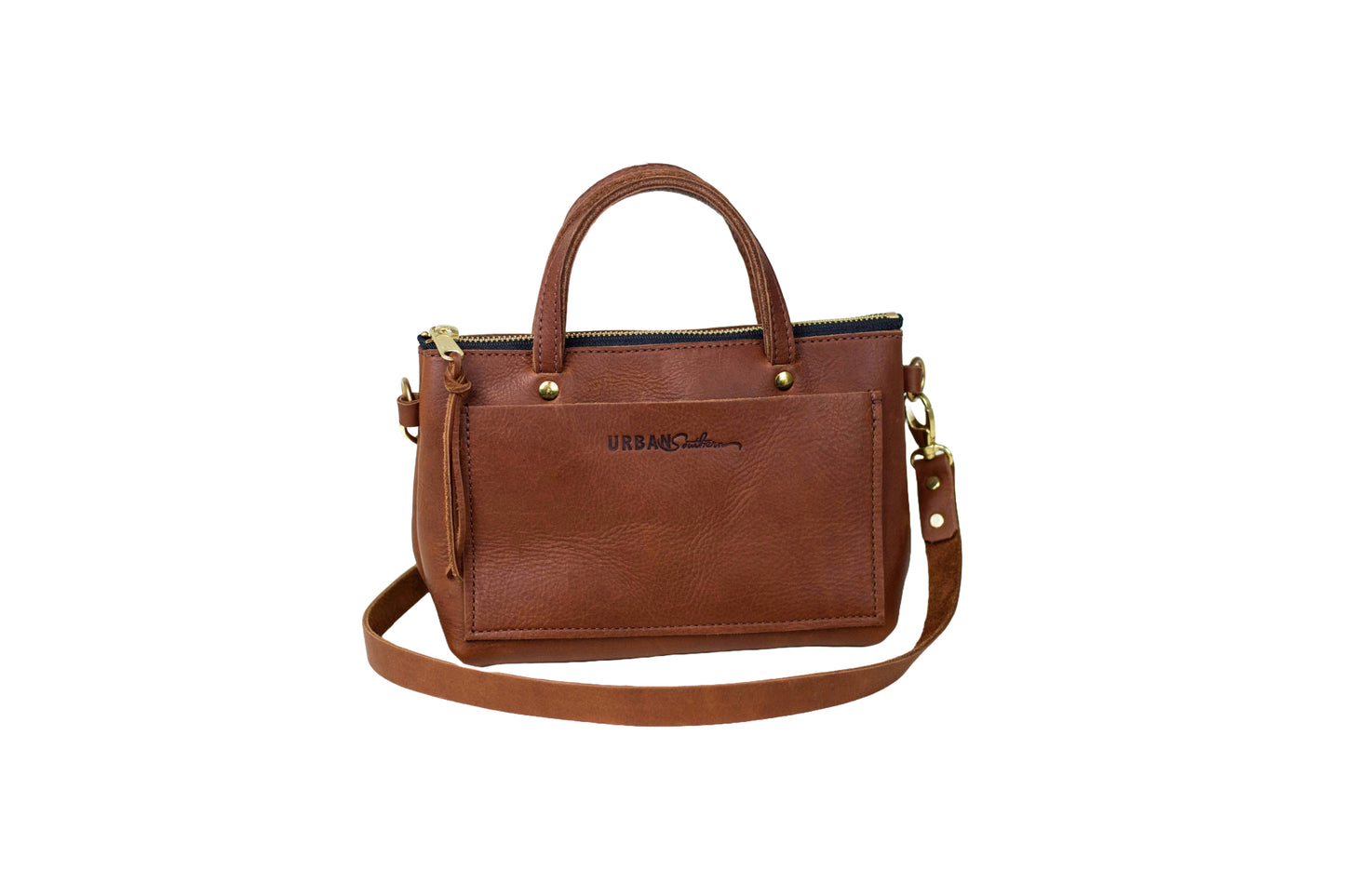 The Urban Southern handcrafted leather Cassidy Crossbody in Cognac with brass accents, zipper, and engraved Urban Southern logo.