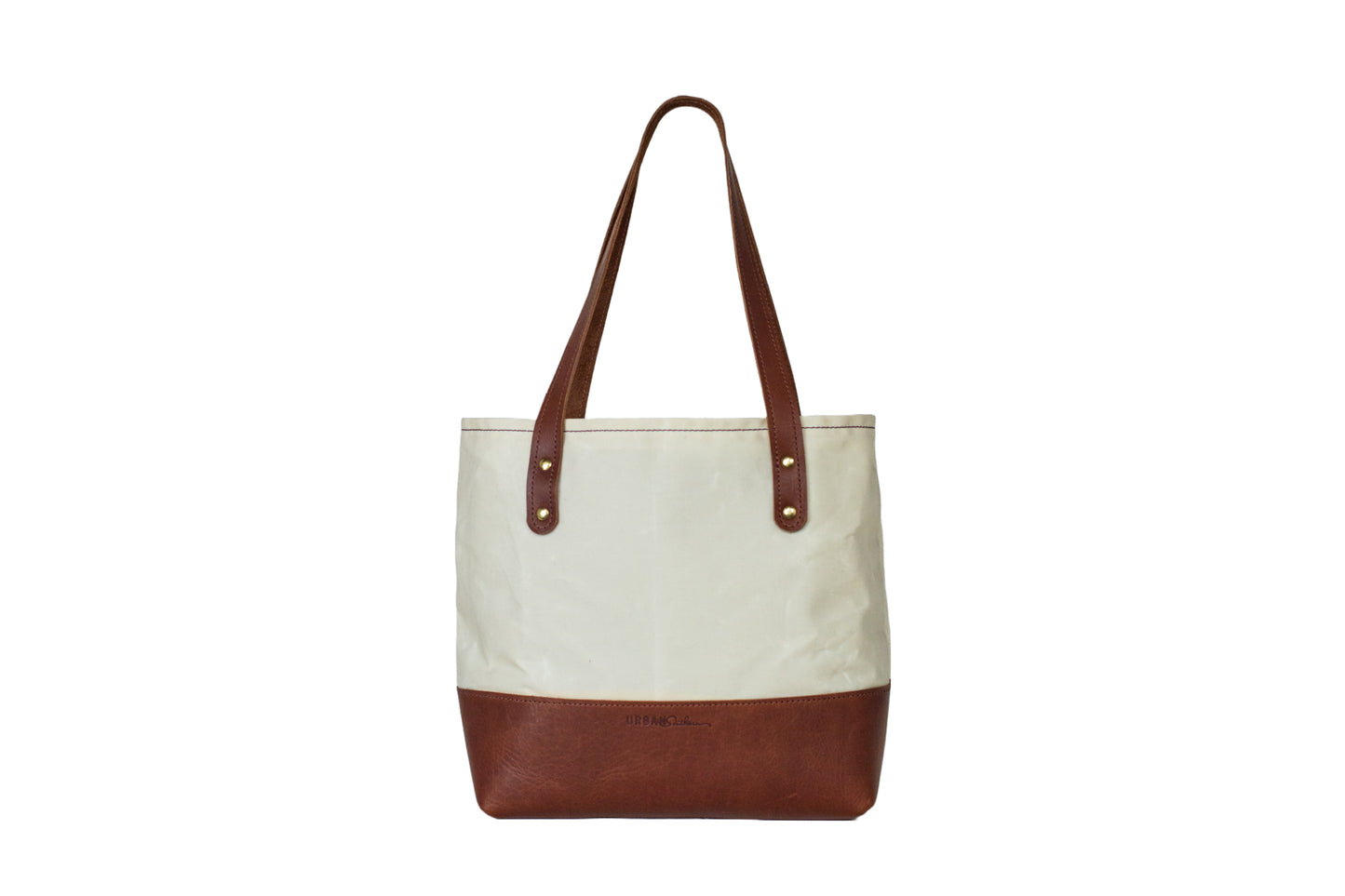 The Urban Southern handcrafted Classic Canvas Tote in Cream, with leather strap, brass hardware, and engraved Urban Southern logo.
