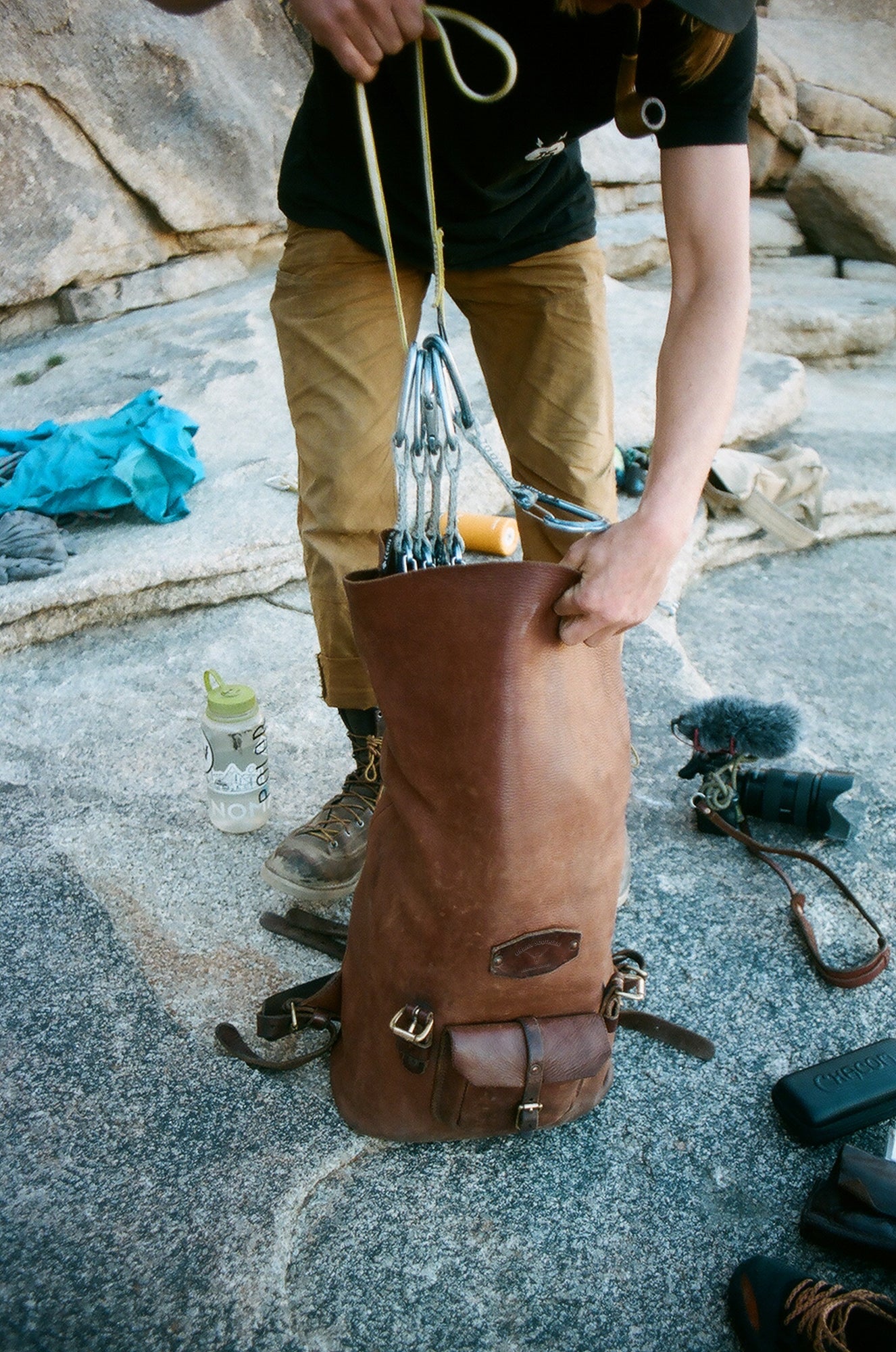 A man unrolls the rolltop backpack to insert rock climbing gear into the bag.