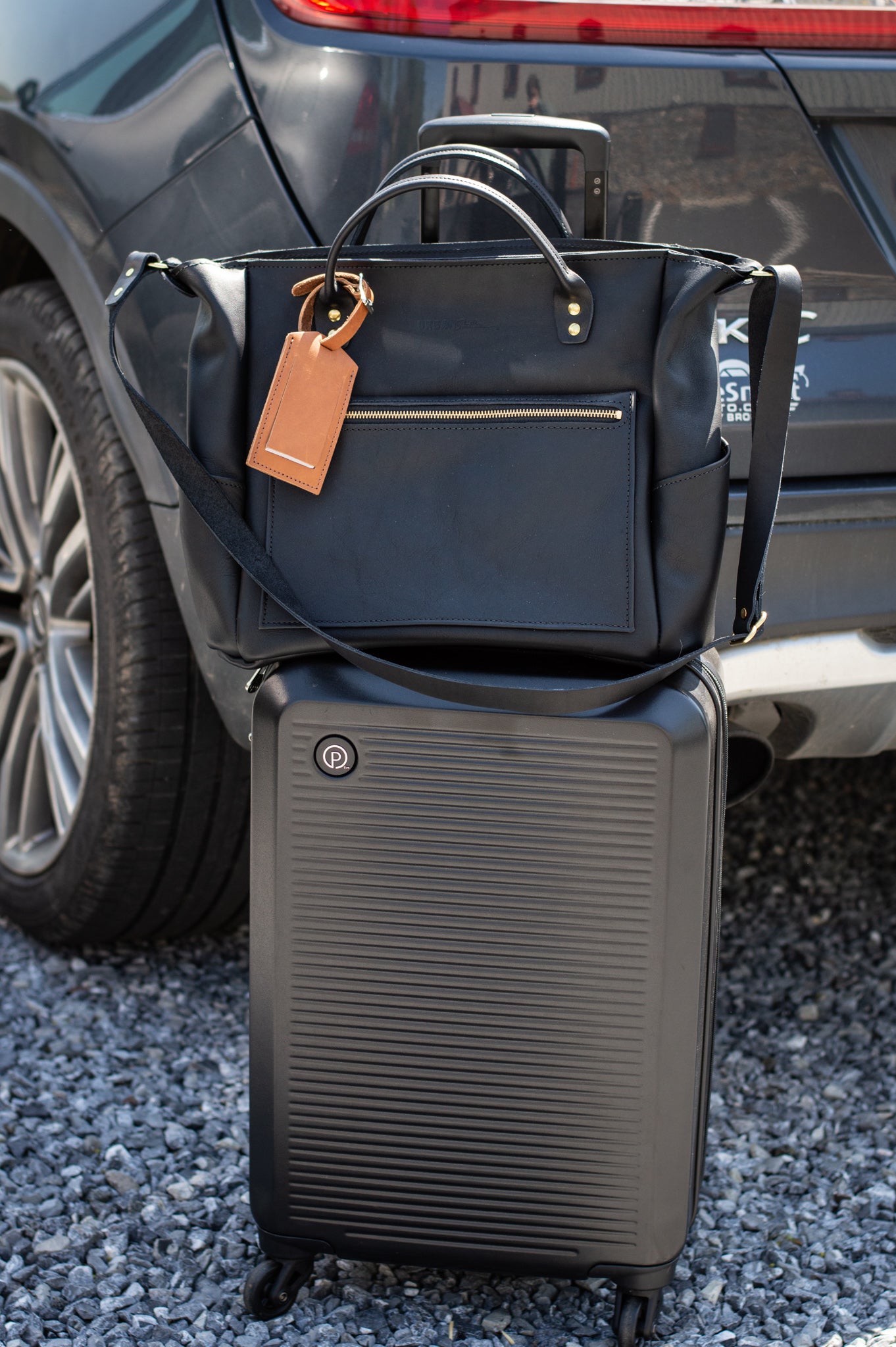 The Urban Southern handcrafted leather luggage tag is attached to the handle of the Legacy Voyager bag.