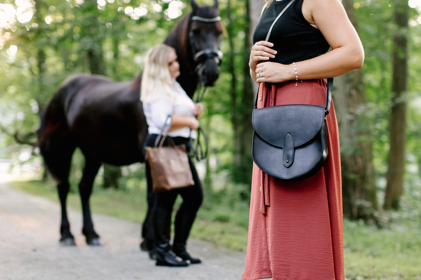 A woman has the adjustable strap set so that the top of the Heritage Saddlebag falls just below her hip, with the bottom of the bag landing just above her knee.
