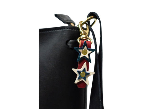 Black handbag with a decorative red, white & blue star charm on a white background