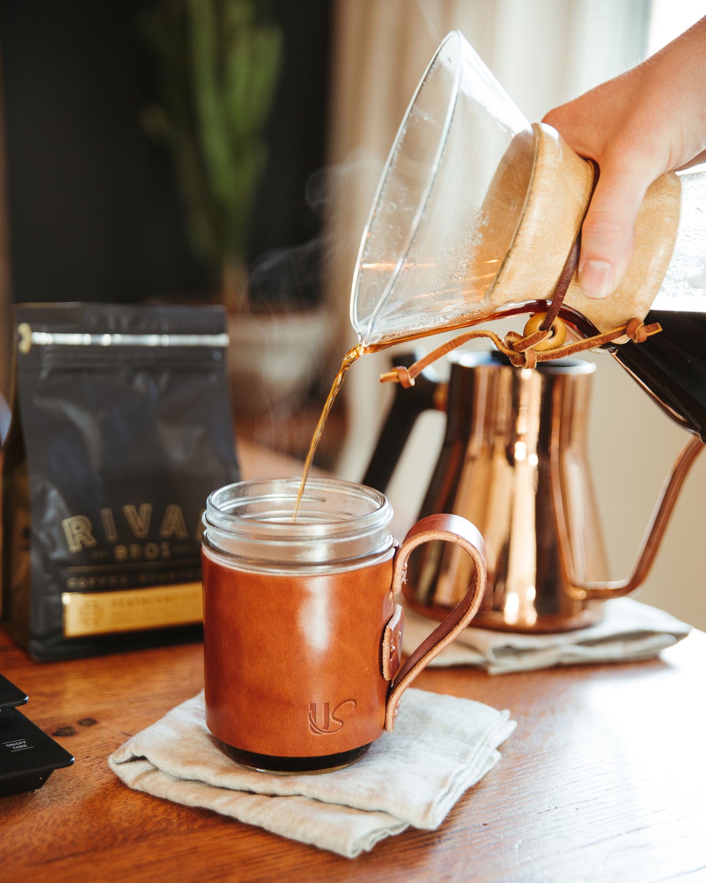 A man pours his freshly brewed coffee into a leather wrapped Mason Jar Mug.