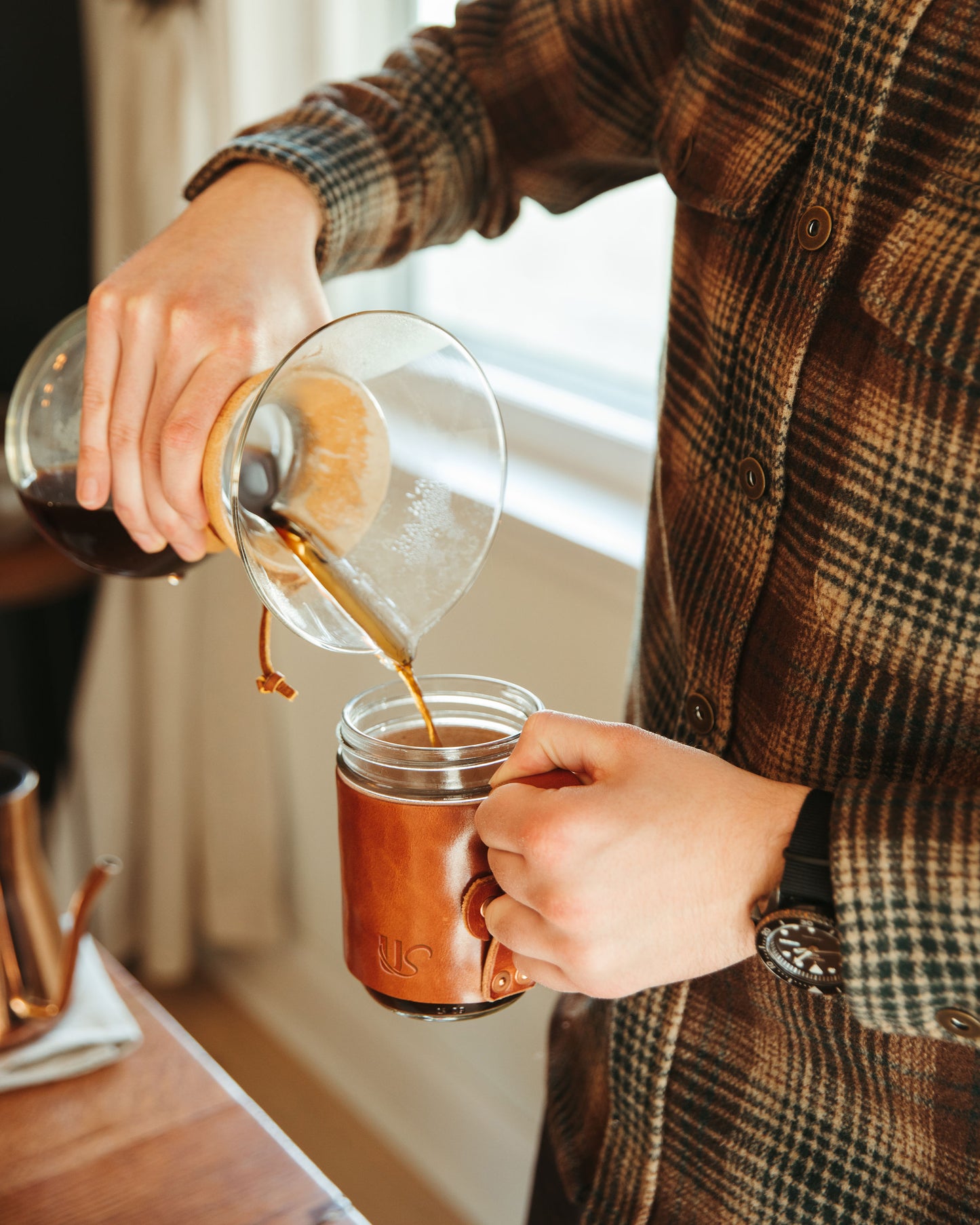 A man pours coffee into his unique leather wrapped Mason Jar Mug.