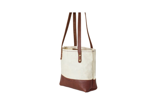 The Urban Southern Mini Canvas Tote features two leather straps and brass accents.