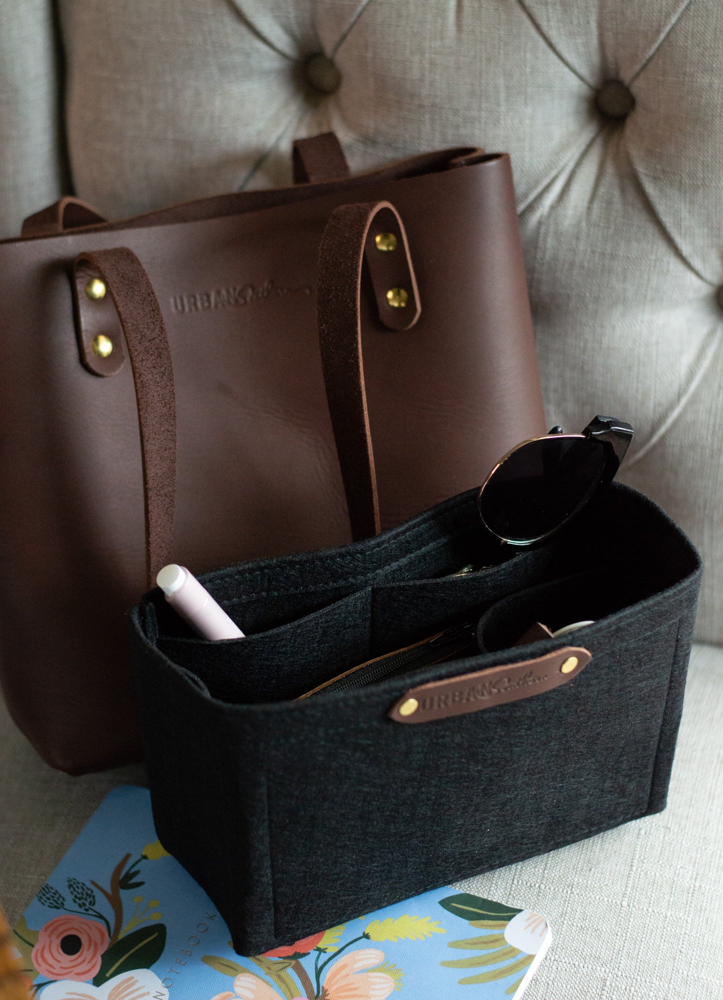 A chestnut Mini Urban Tote sits on a plush chair, next to a Mini Tote Insert.