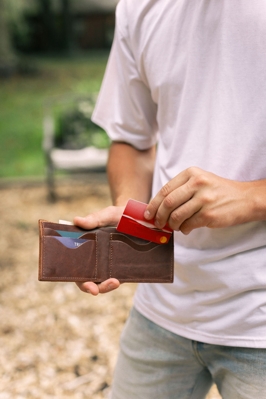 a man removes a credit card from his leather bifold wallet