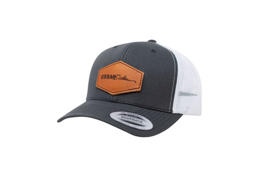 A side angle view of a charcoal & white leather patch hat, featuring the classic Urban Southern logo on a hexagon leather patch.