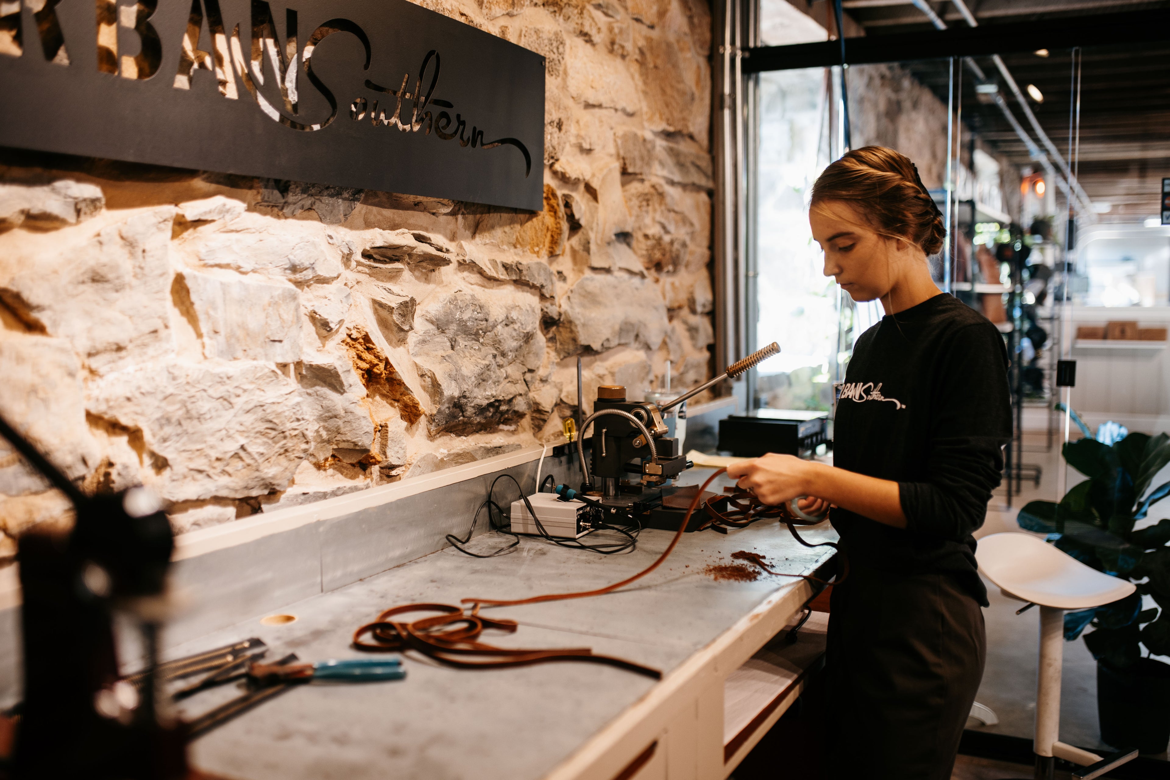 A woman in a workshop cuts pieces of a leather handbag.