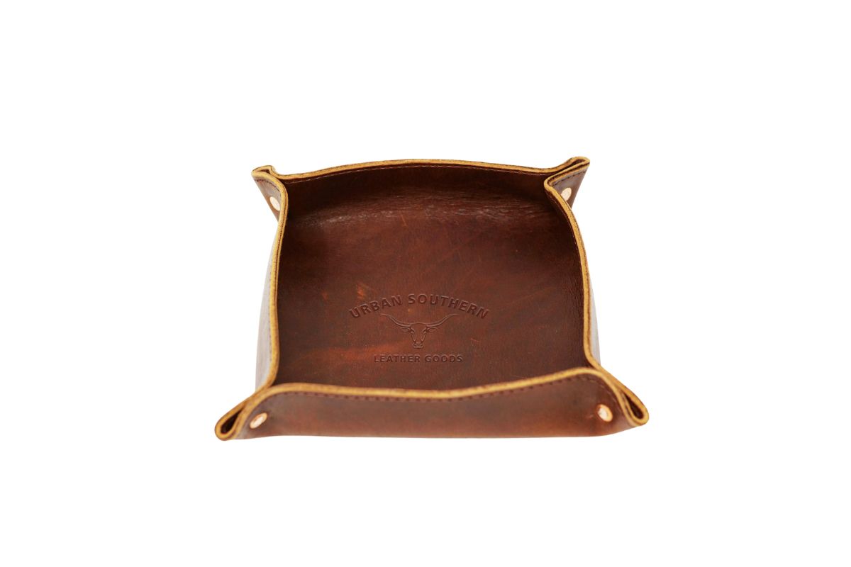 A close up view of the valet tray, featuring rich, full-grain leather, copper rivets & a rustic urban southern logo.