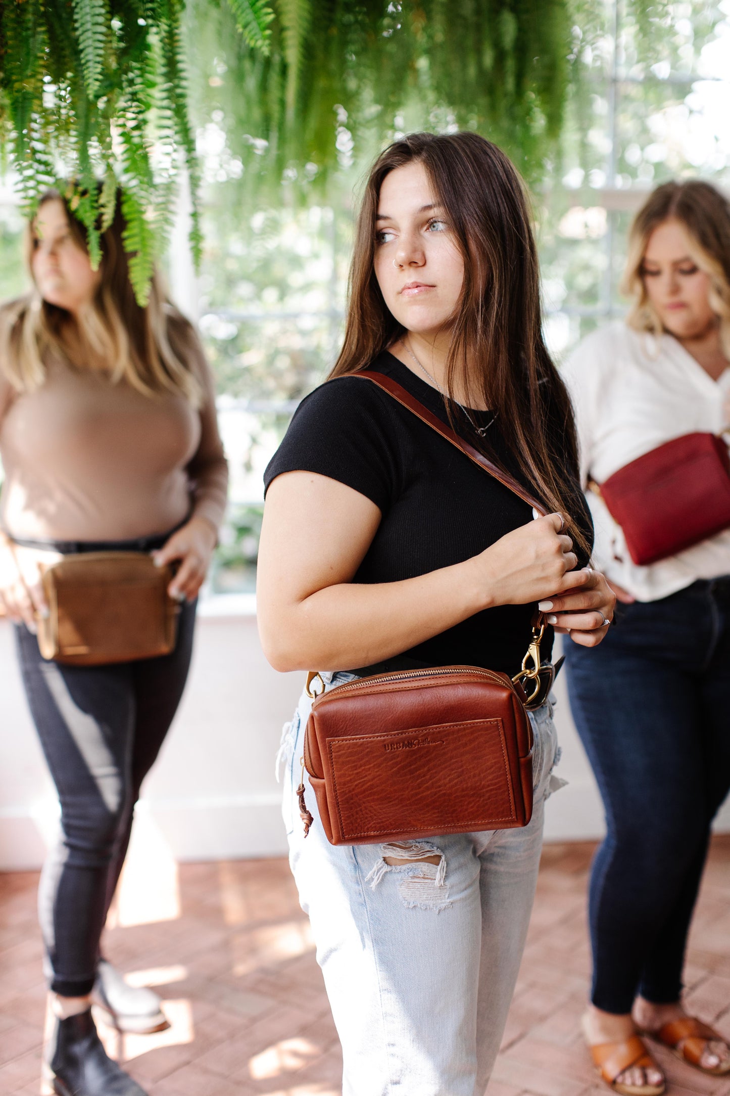 A woman wears a cognac Urban Sling on her shoulder.