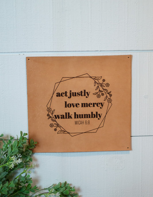 The square leather sign is shown mounted on a white wall.