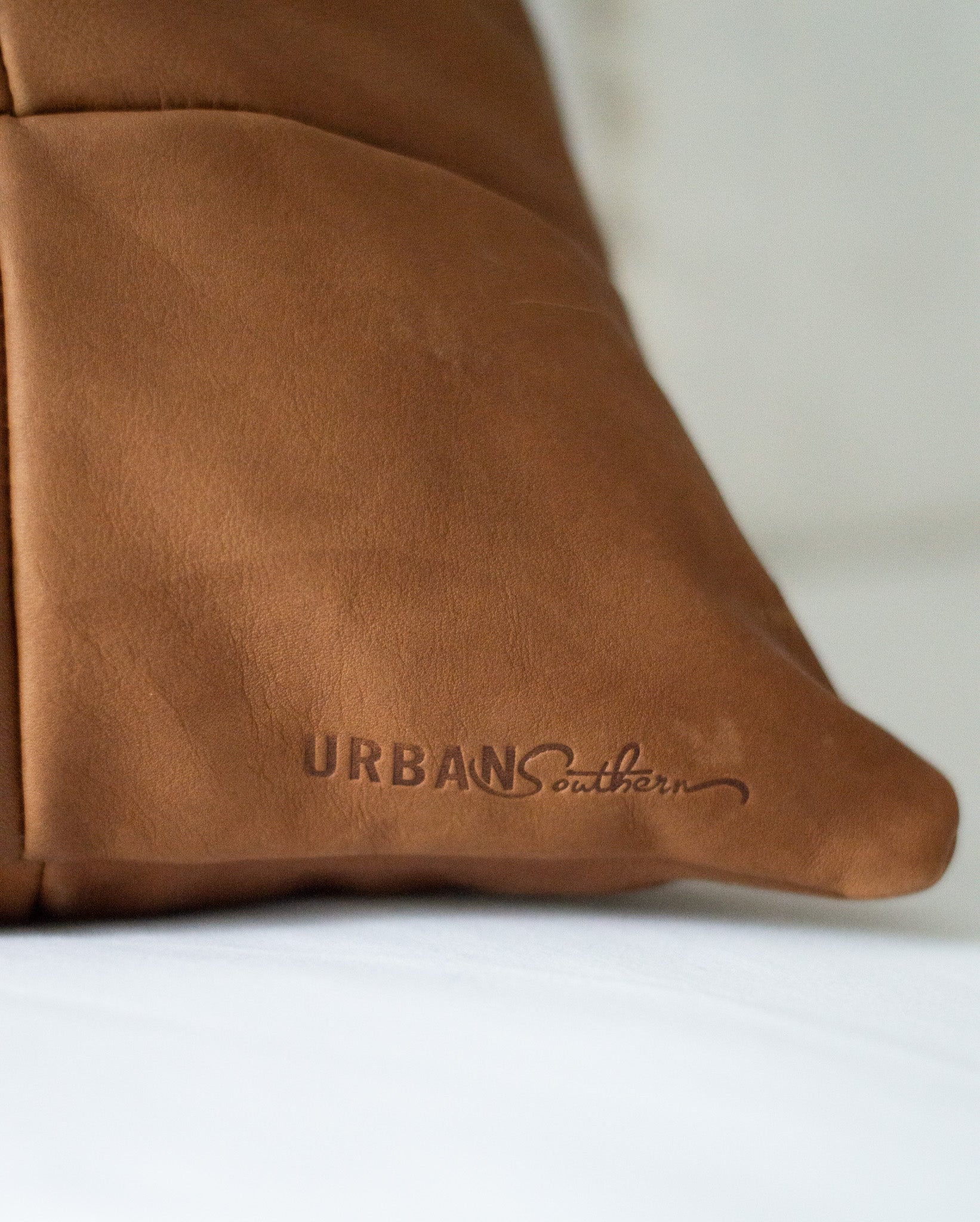 The bottom corner of the Large Leather Pillow features the engraved Urban Southern logo.