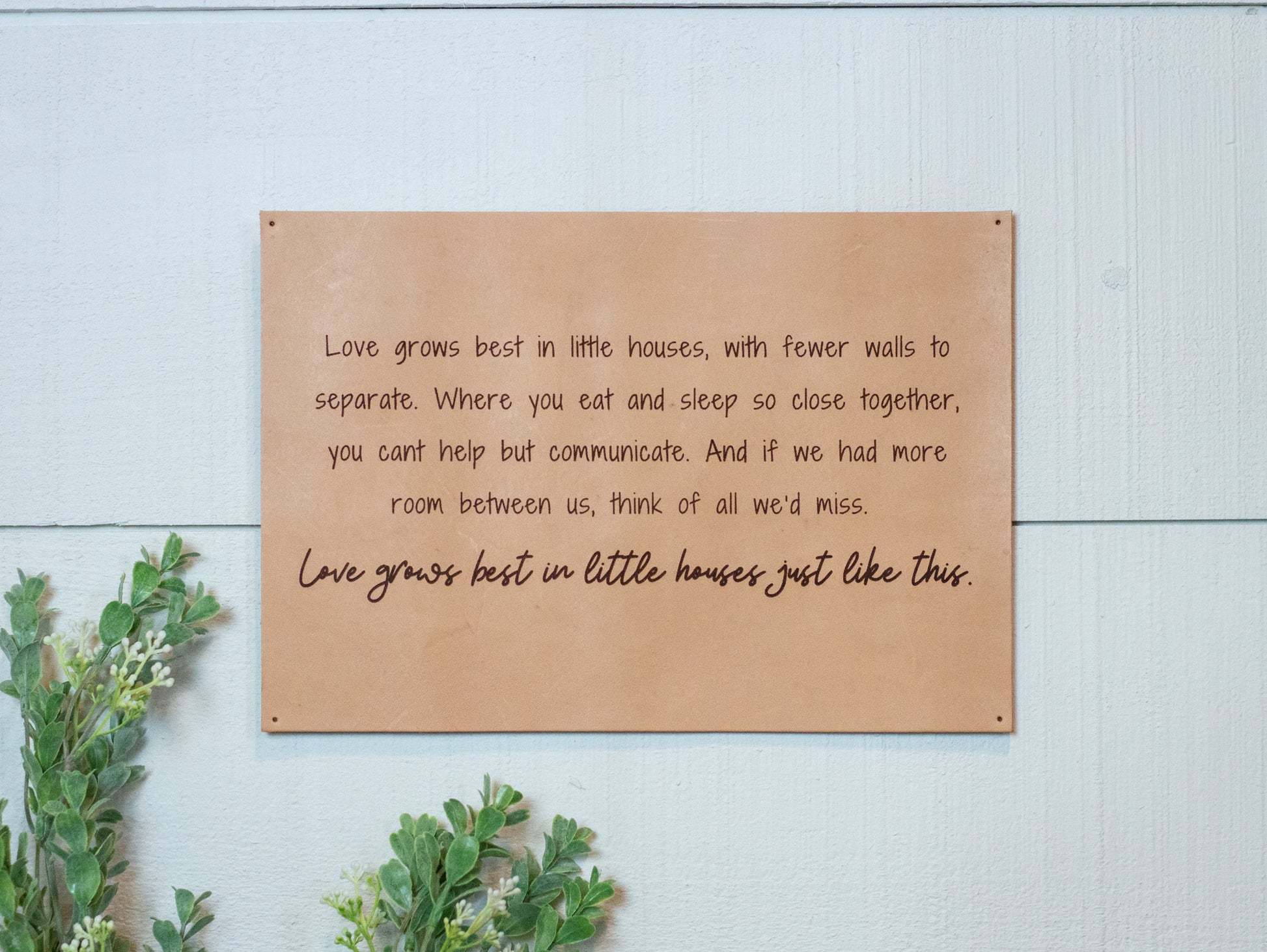 The Urban Southern handcrafted leather "Love Grows Best" sign hangs on the wall.
