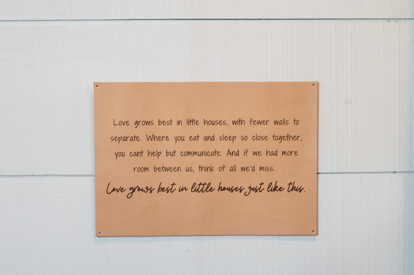 The Urban Southern handcrafted leather "Love Grows Best" sign hangs on a wall.