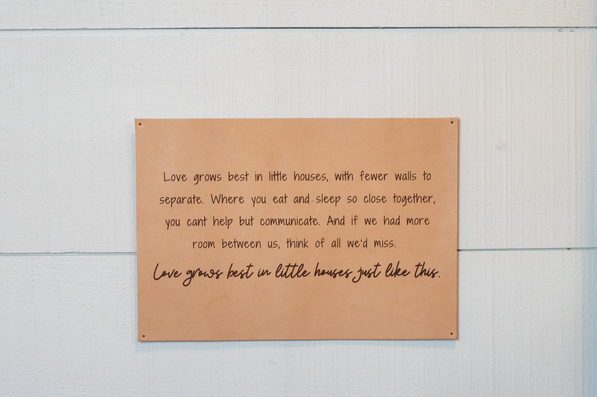 The Urban Southern handcrafted leather "Love Grows Best" sign hangs on a wall.