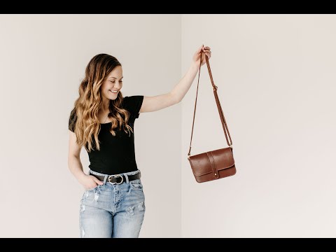 Video tour demonstrating the features of the Lancaster 5-Pocket Crossbody.  A woman is showcasing the brass post closure on the front of the bag, as well as the 5 interior pockets and credit card slots.