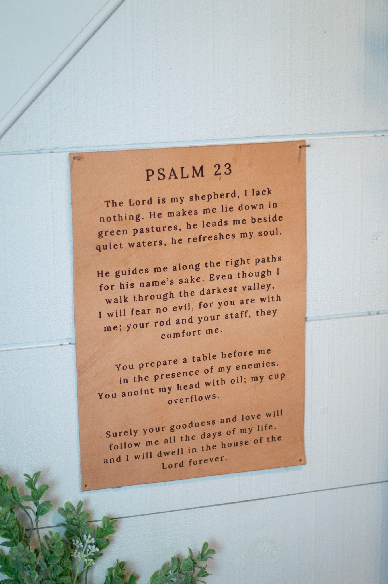 Psalm 23 leather sign mounted on white wall.
