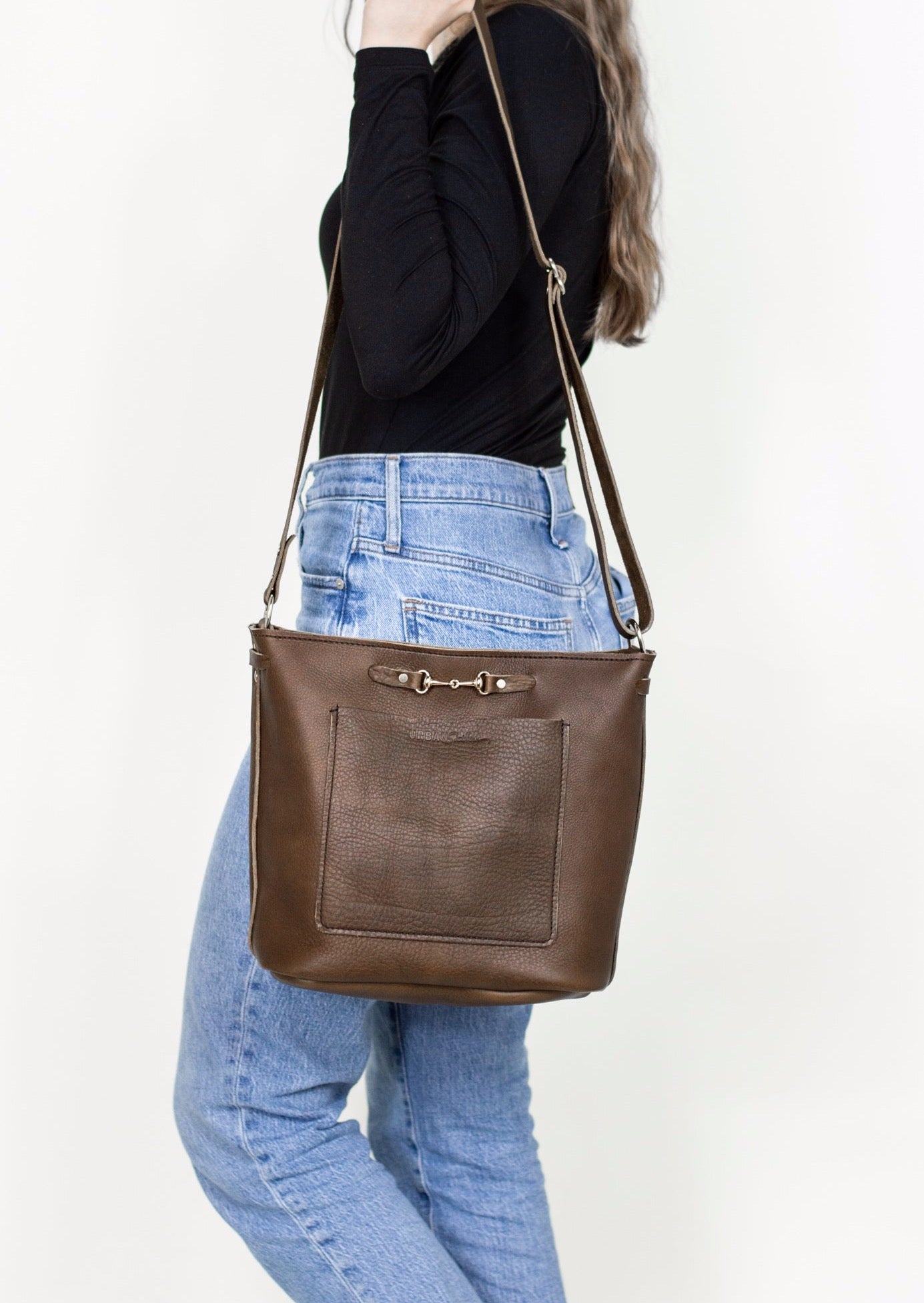 A woman holds a mocha Lexington Julep handbag on her shoulder.