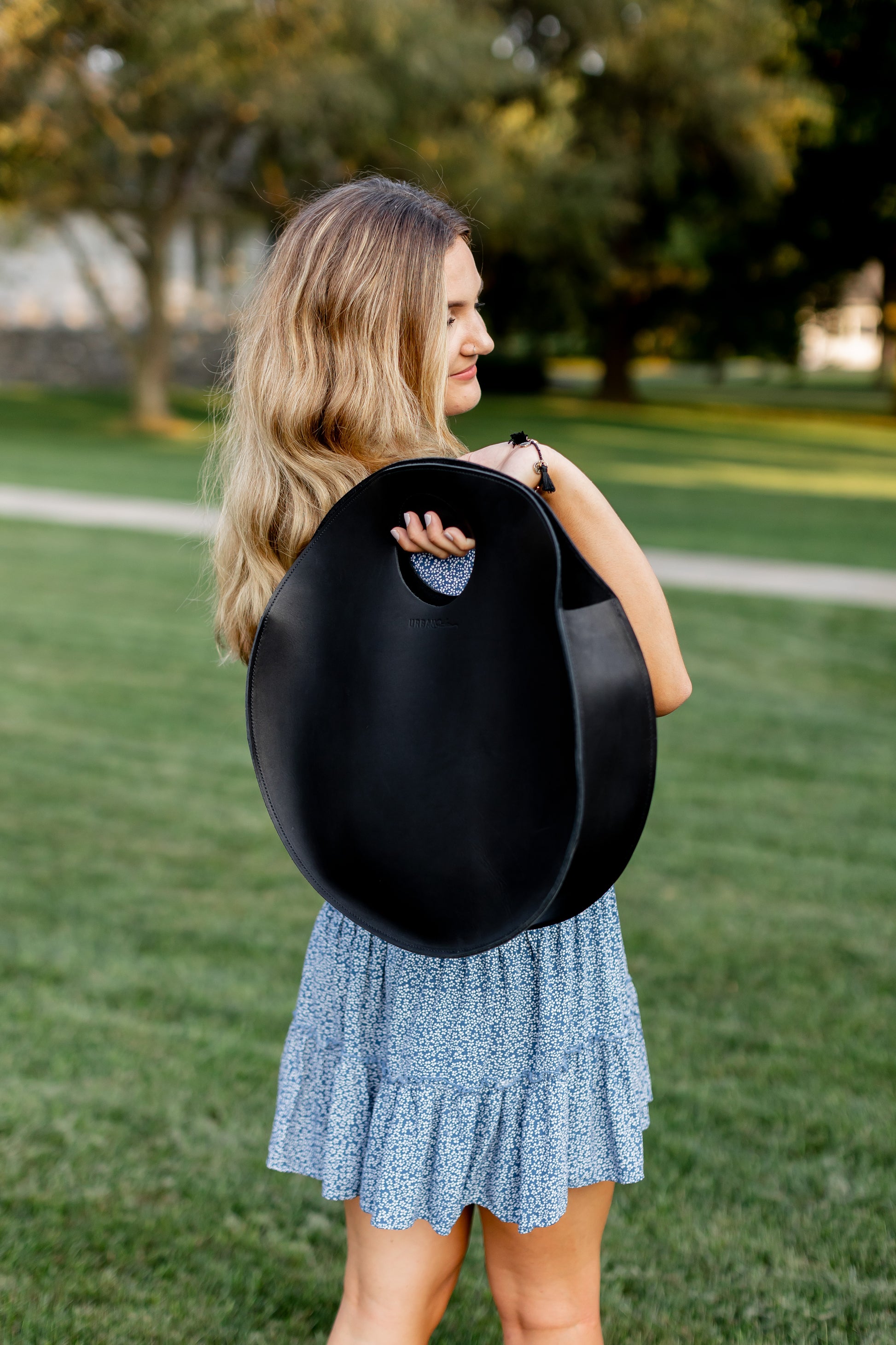 A woman carries the Carrollton Circle Tote in Black.