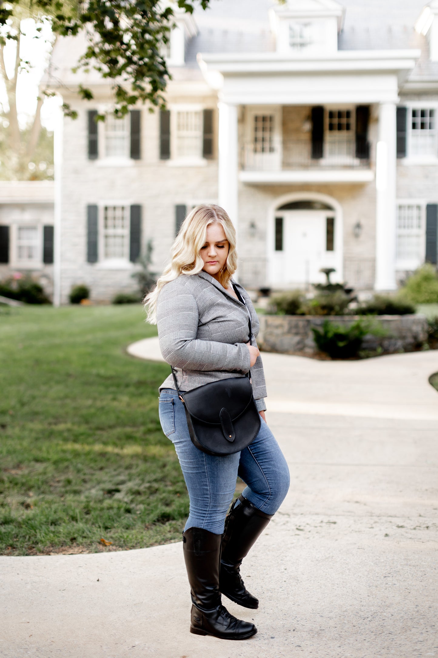 A woman carries the Heritage Saddlebag in Black across her chest like a crossbody bag.
