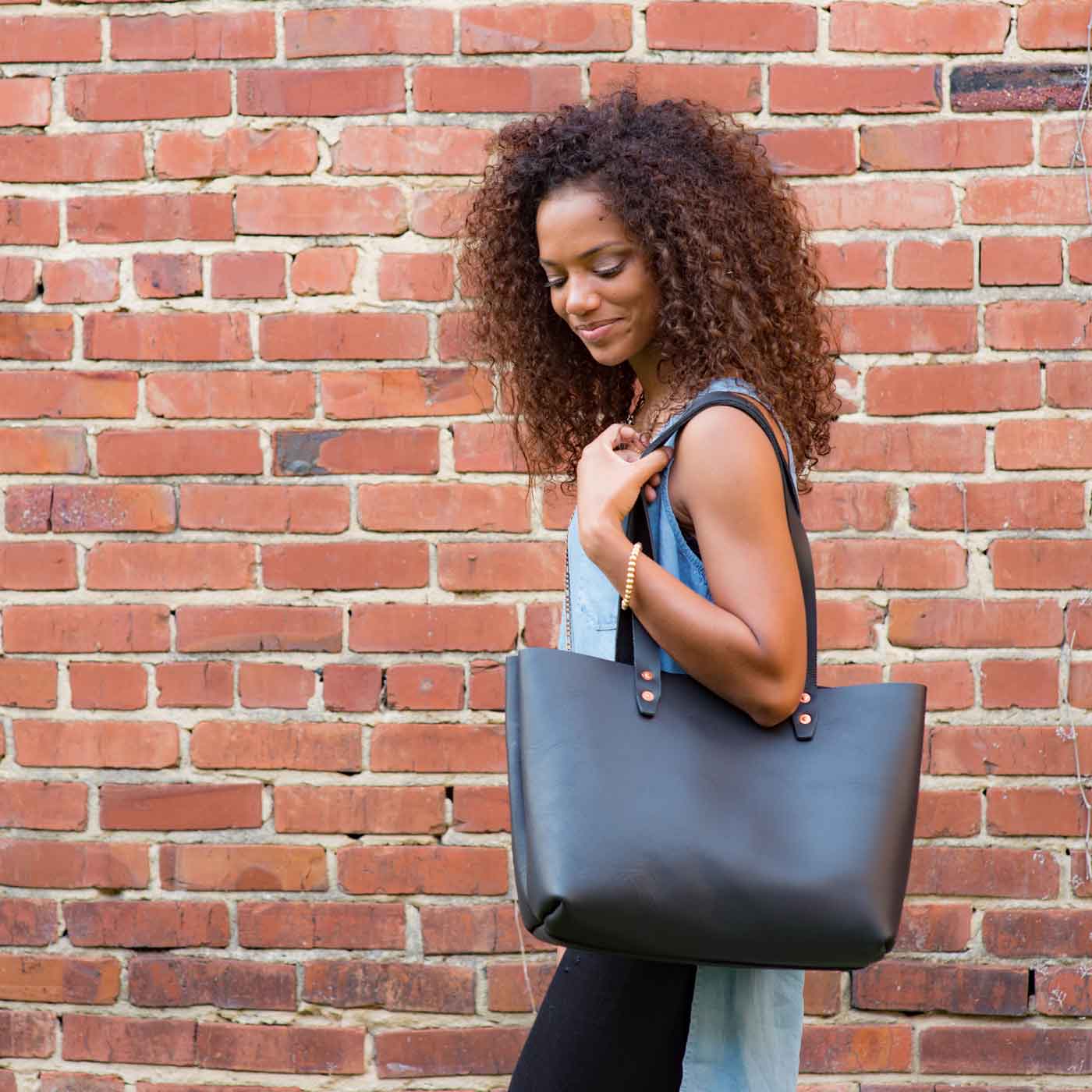 A woman carries the Urban Tote in Black over her shoulder.