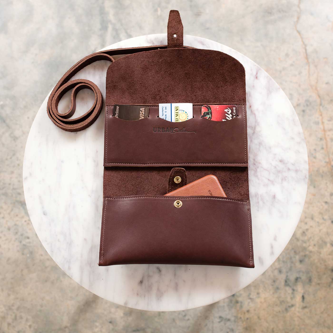 Inside the Crossbody Wallet, a credit card, shopping card, and business card are shown in the three card slots, and a smart-phone is shown in the lower pocket.