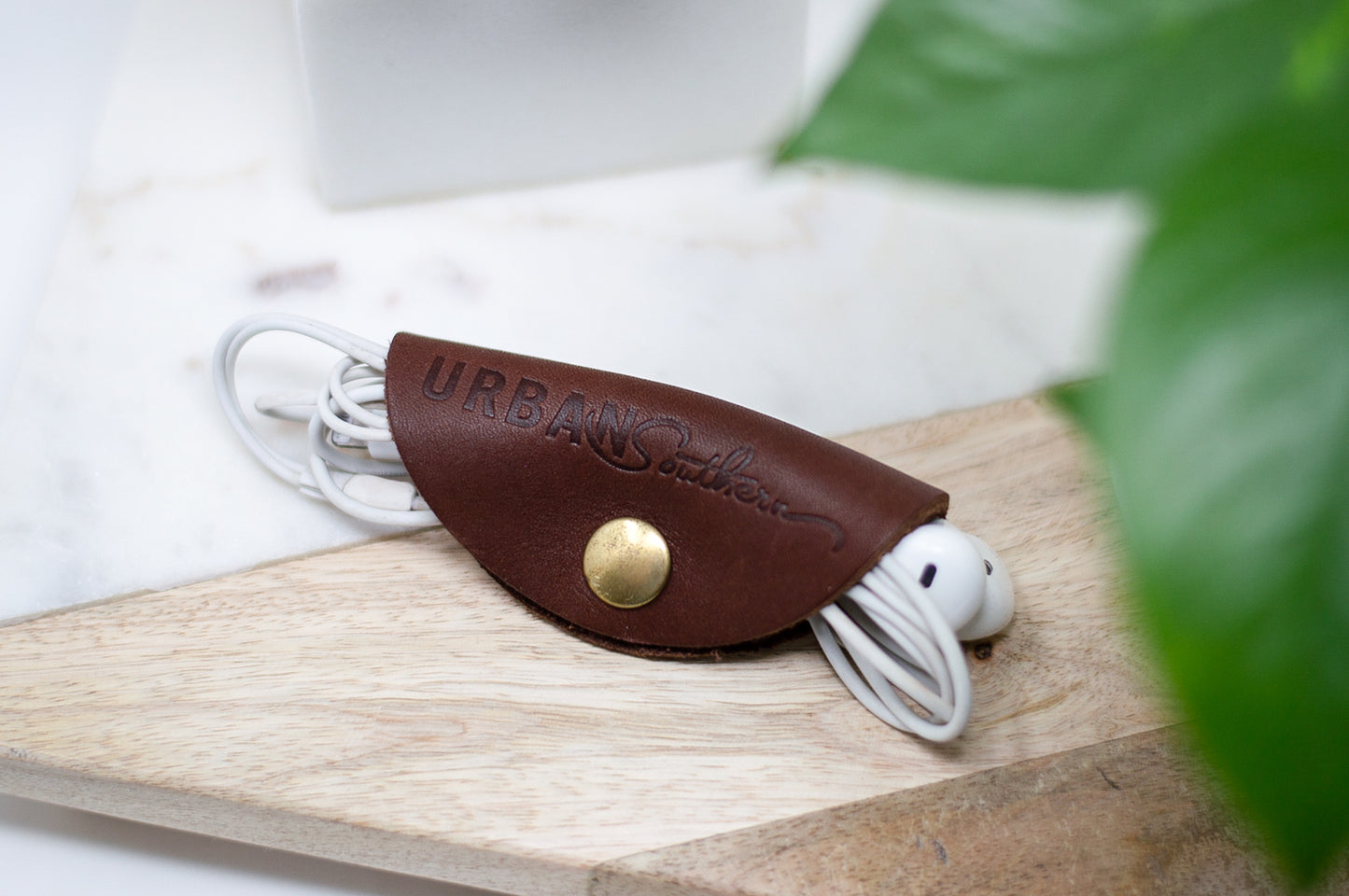 An Urban Cord Wrap in chestnut leather, neatly organizes a pair of headphones.