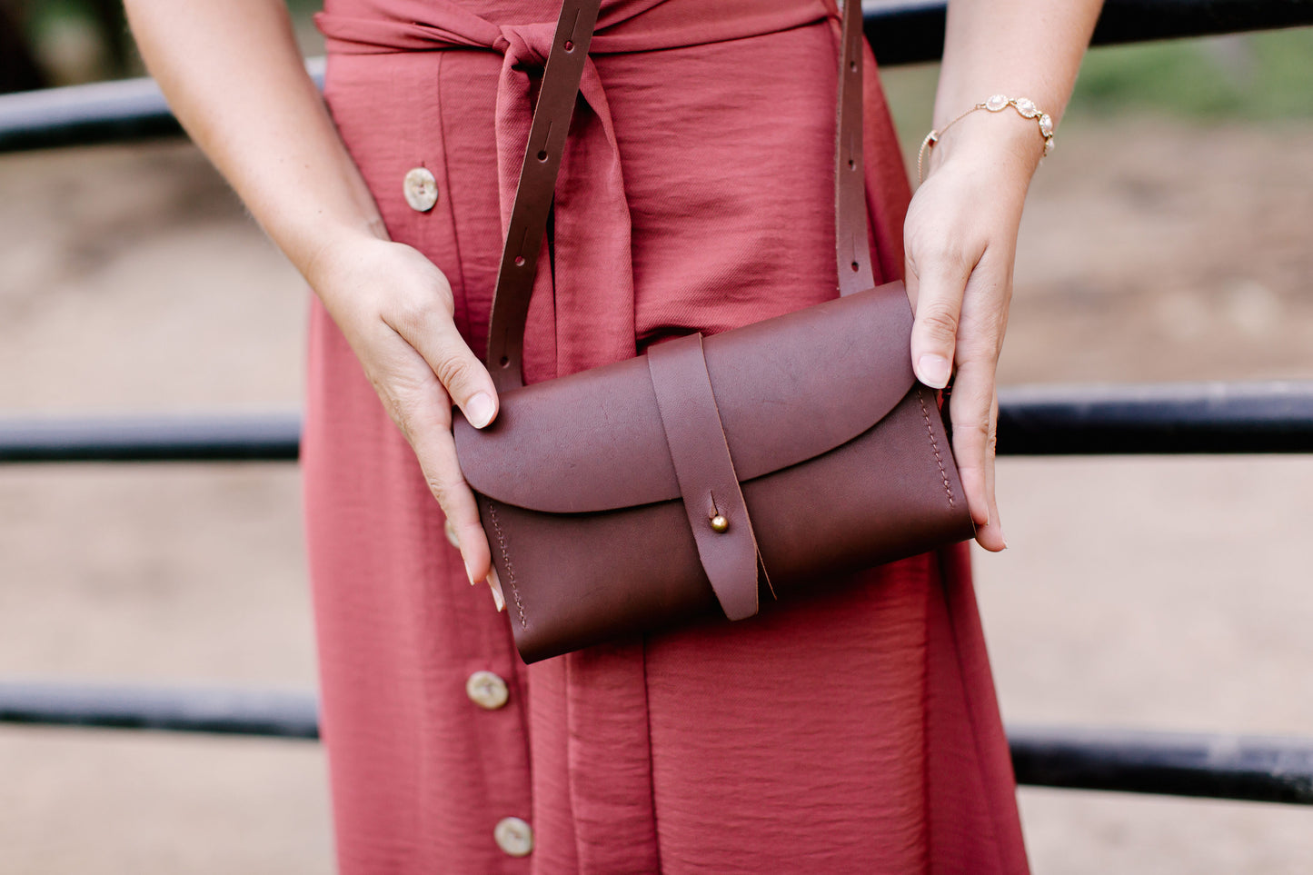 A woman holds the Crossbody Wallet in Chestnut Brown.