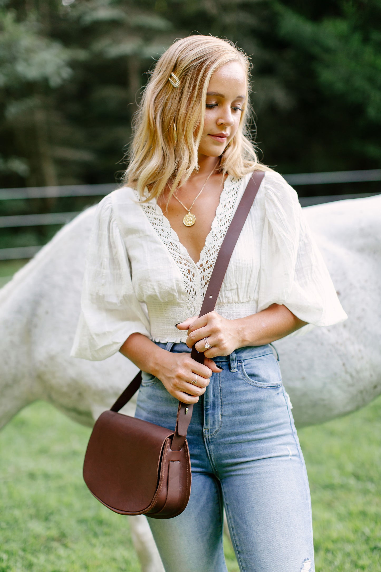 A woman carries the Half Moon Crossbody in Chestnut Brown with the strap adjusted so the bag falls at hip level.