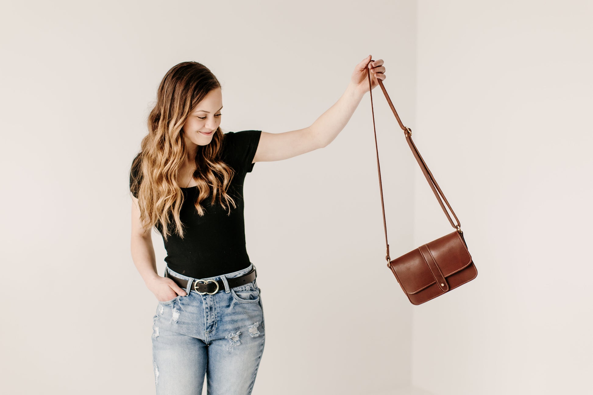 A woman carries the Lancaster 5-Pocket Crossbody bag in Chestnut Brown.