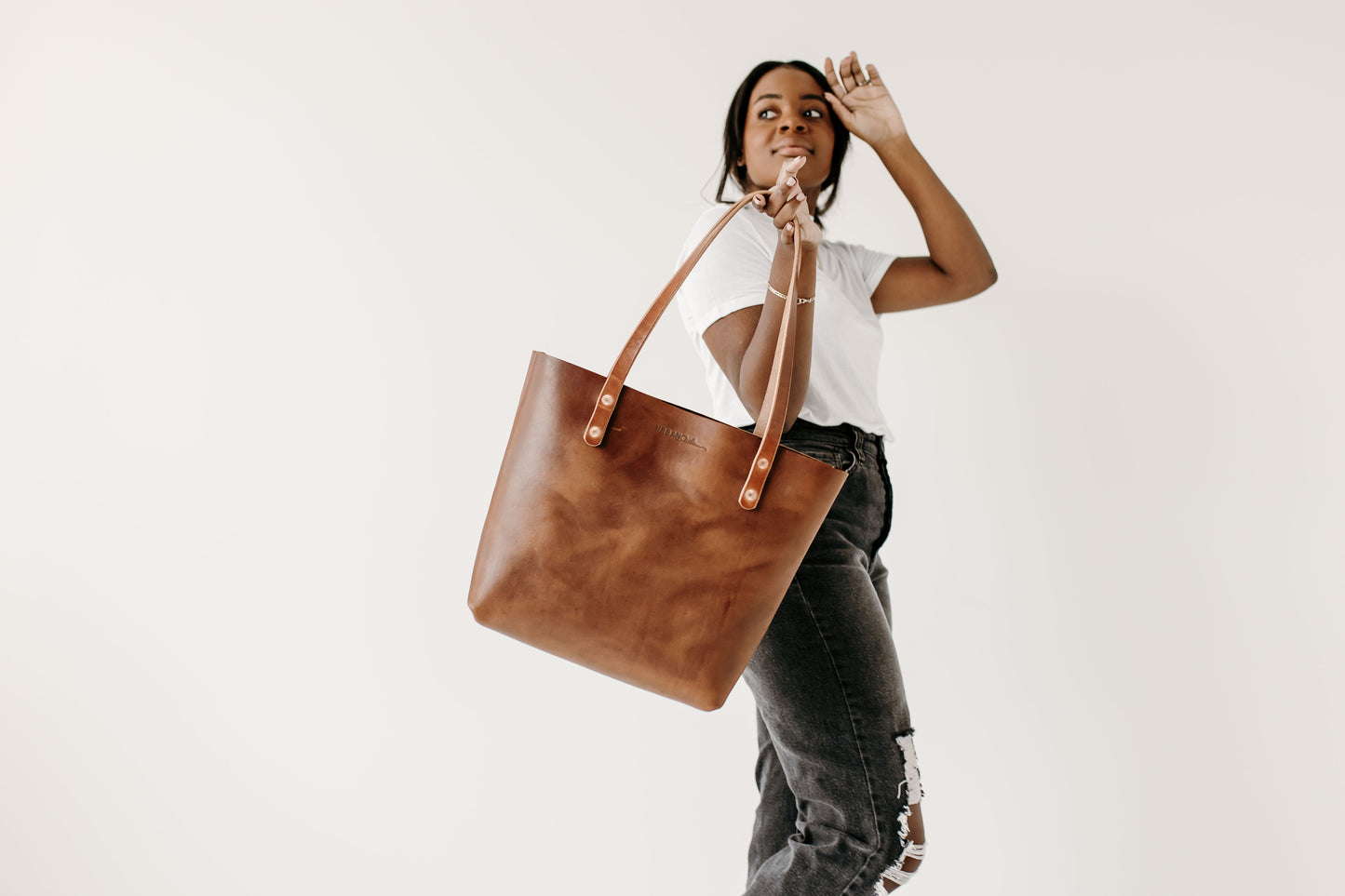 A woman carries the Urban Southern Classic Tote by the handles.