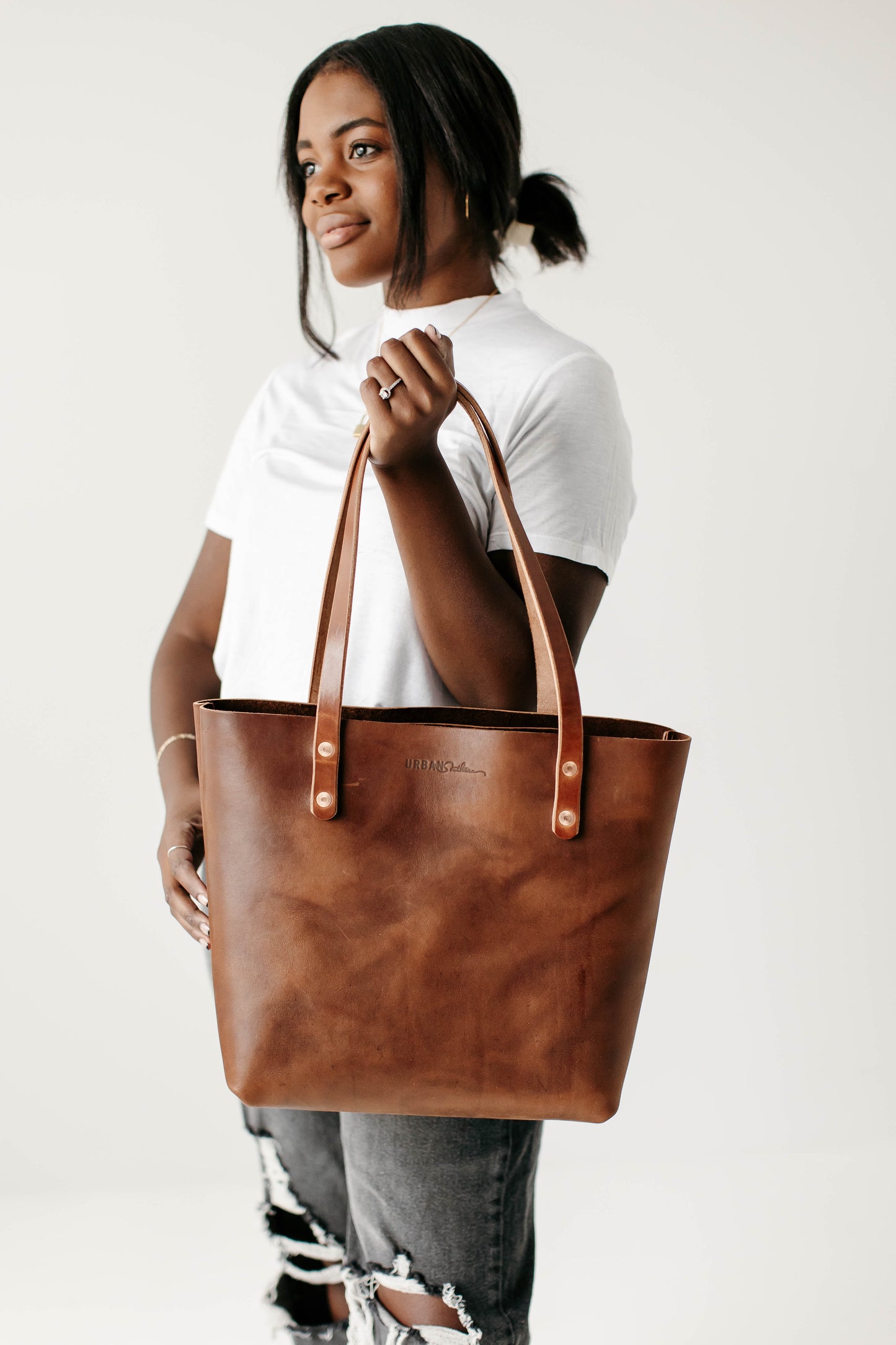 A woman holds up the Classic Tote by the handles.