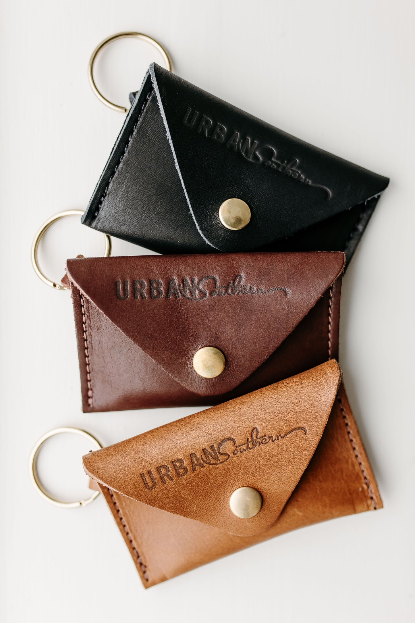 The Urban Southern handcrafted leather Keychain Coin Purse is shown in three different colors: Black, Chestnut Brown, and Honey.