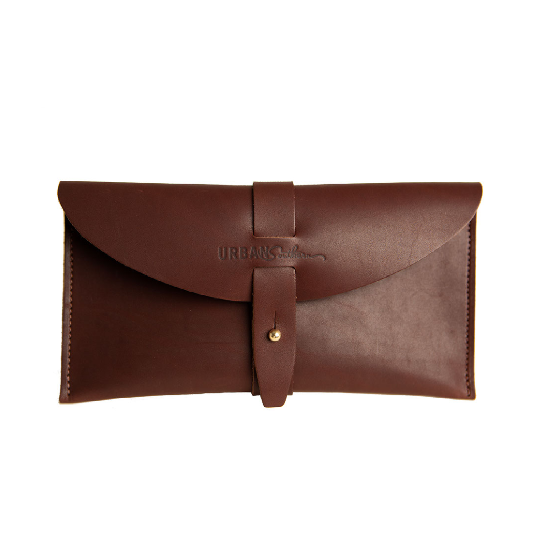 The handcrafted leather 5th Avenue Clutch in Chestnut color, with handmade stitching, engraved Urban Southern logo, leather band and brass post clasp.