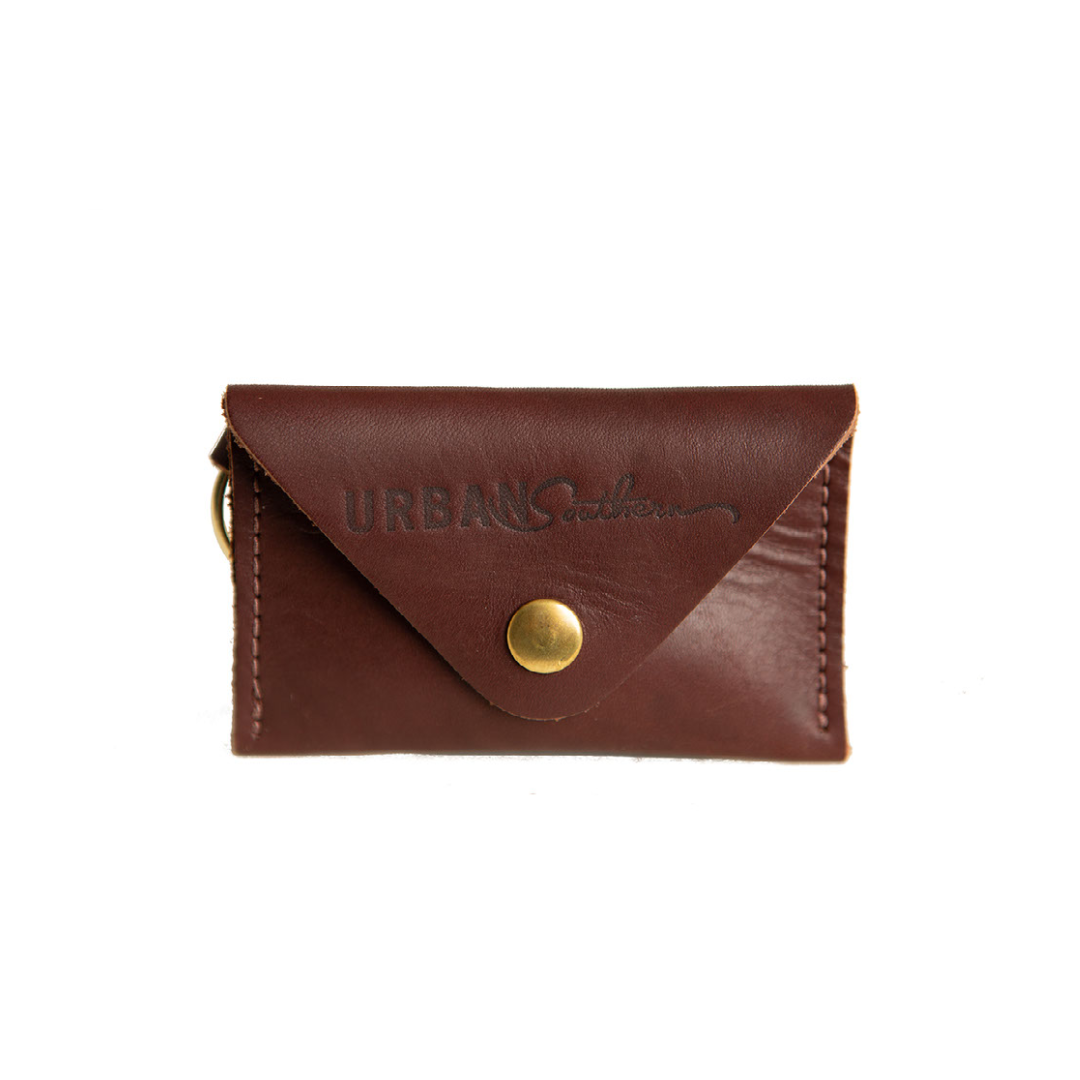 The Urban Southern handcrafted leather Keychain Coin Purse features a brass snap, brass keychain ring, and engraved Urban Southern logo. Shown in Chestnut Brown.