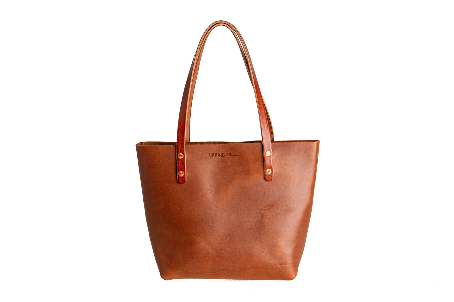 The Urban Southern handcrafted leather Classic Tote is available in Cognac and features two solid straps, brass rivets, and an engraved Urban Southern logo.