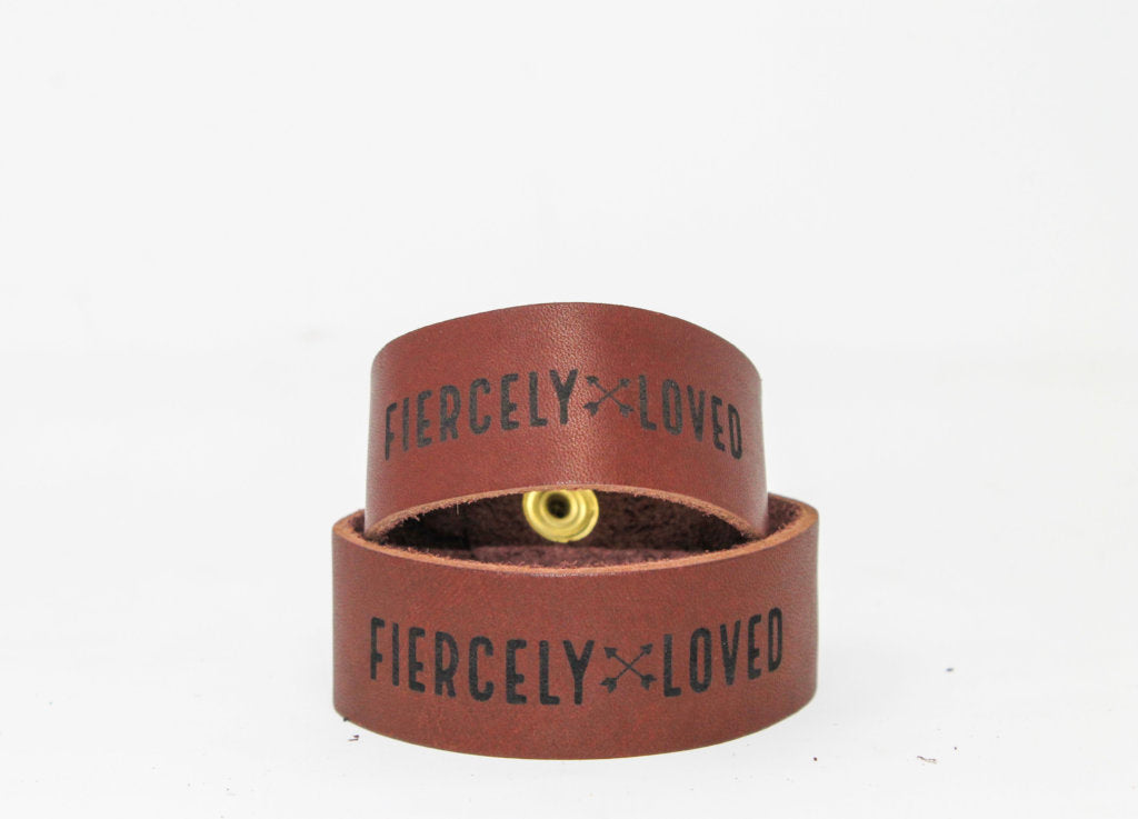 The Urban Southern Fiercely Loved leather cuff bracelet strap comes in Chestnut Brown with charcoal-to-black engraved letters and a brass snap.