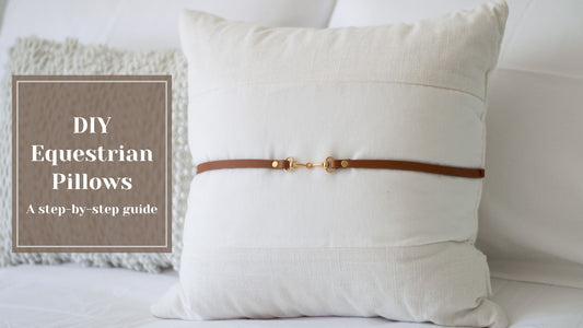 A cream pillow with leather strip & gold bit. 