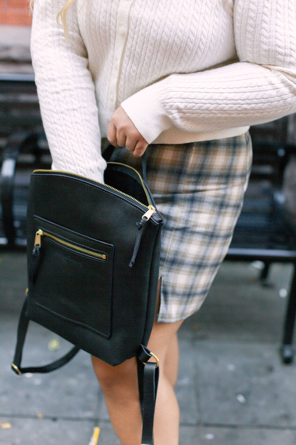 A woman reaches into her Brooklyn Backpack in Black.