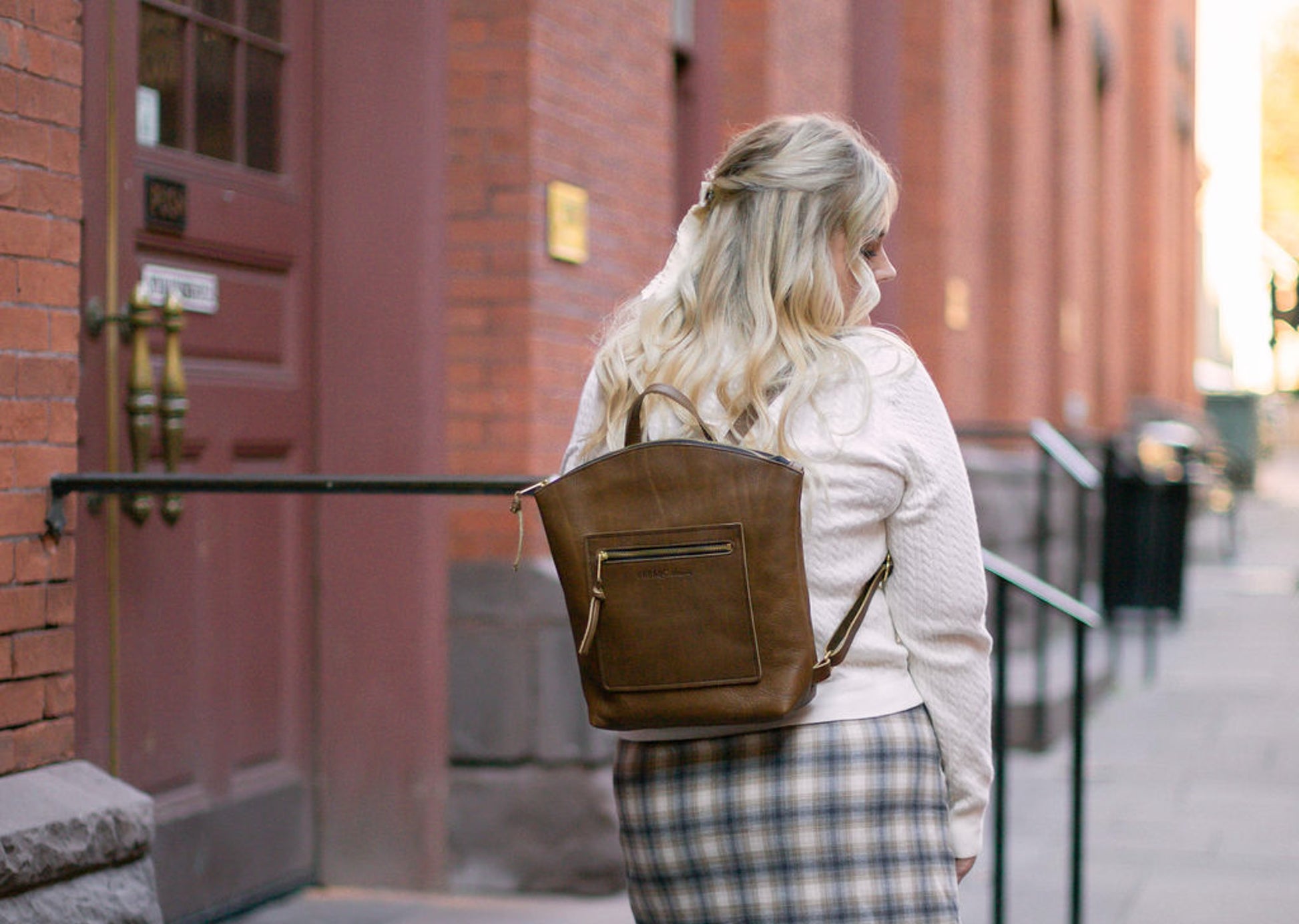A woman carries Brooklyn Backpack in Mocha on her back.