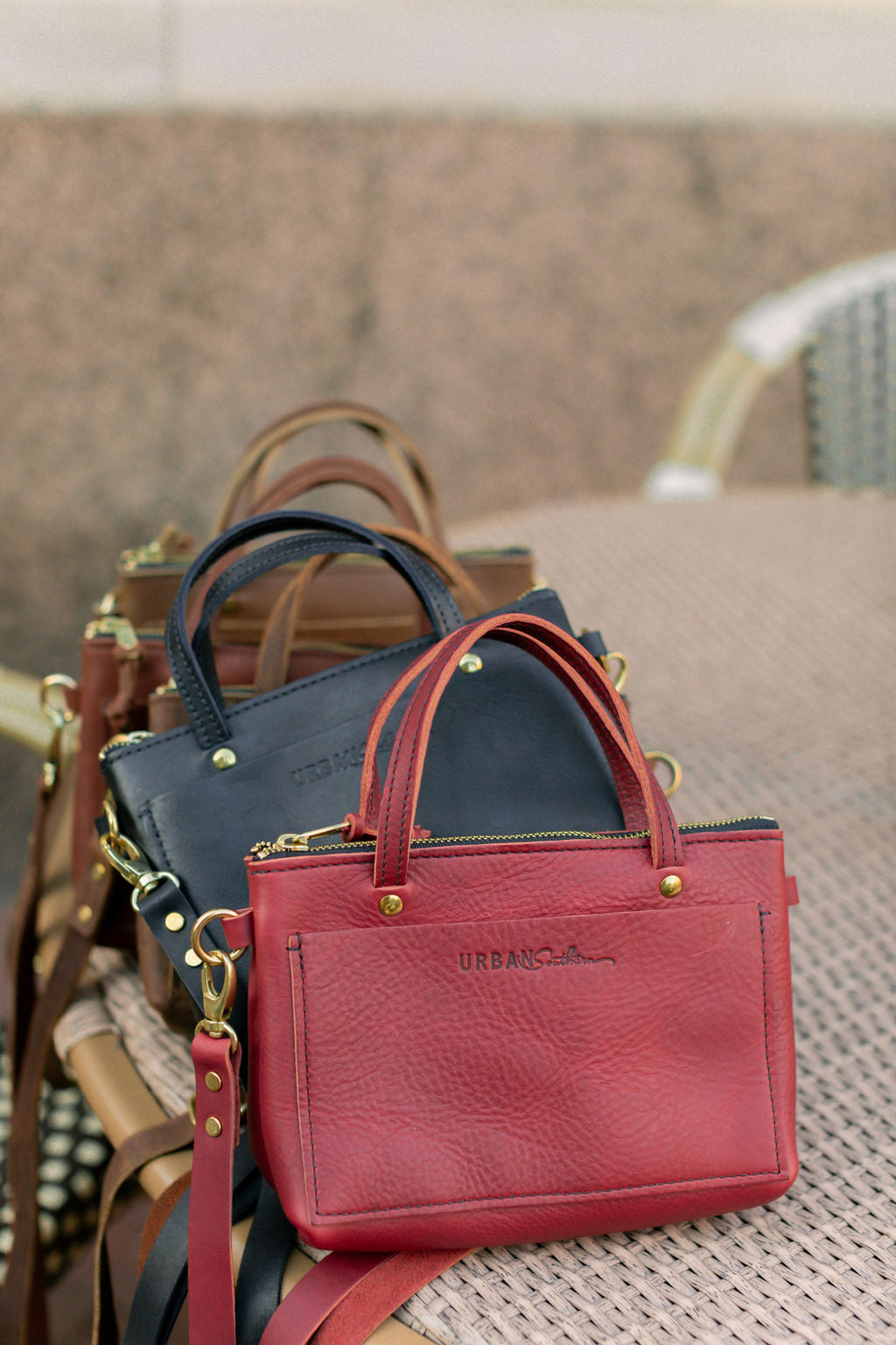 The Urban Southern handcrafted leather Cassidy Crossbody bag in Merlot, with additional colors stacked behind it.