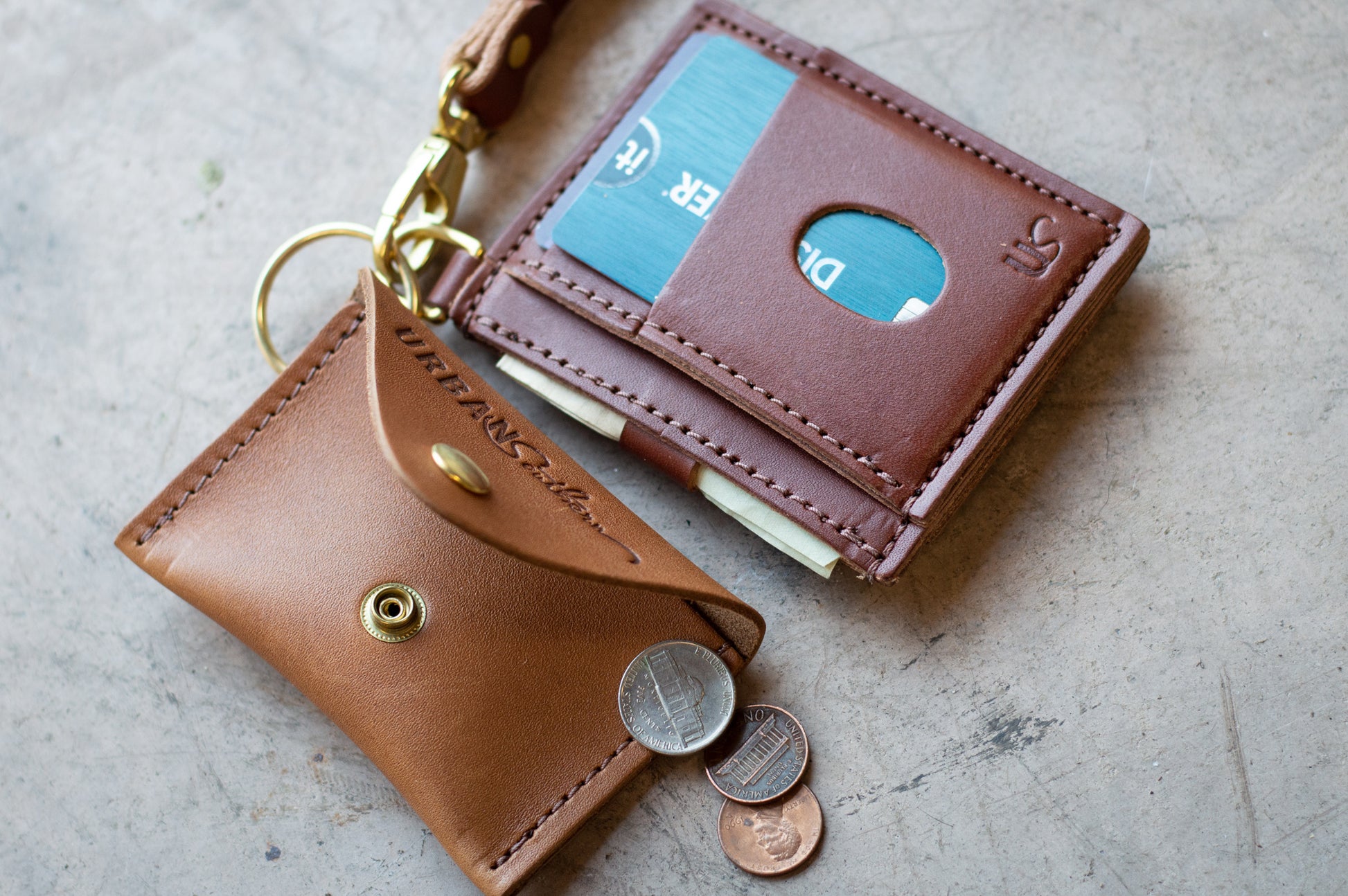 The Everly Wristlet Wallet in Chestnut Brown is shown with the Urban Southern Keychain Coin Purse in Honey, both clipped to the Wristlet Wallet brass clip for easy carrying.