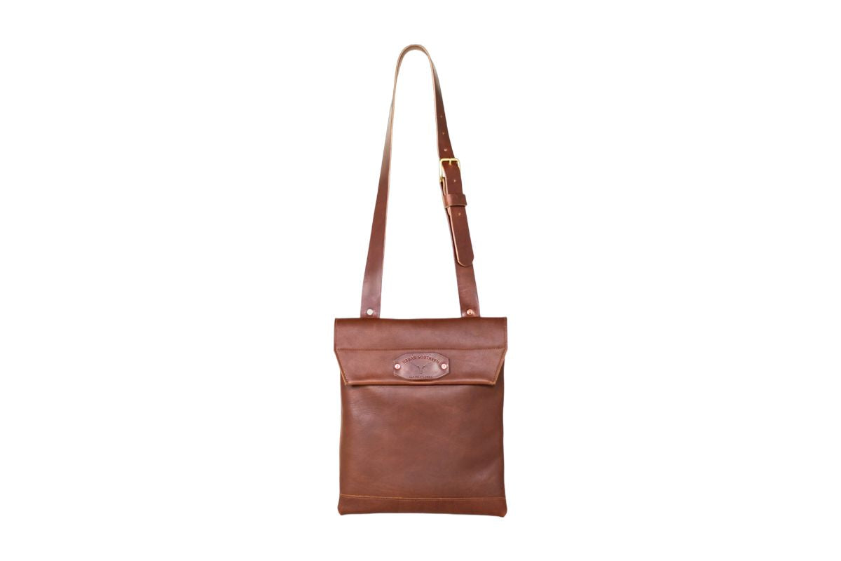 Brown leather courier bag with a strap on a white background