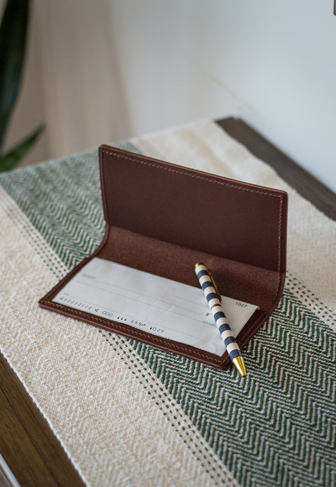 The Urban Southern handcrafted leather Checkbook Cover with a checkbook inserted into one of the leather pockets.