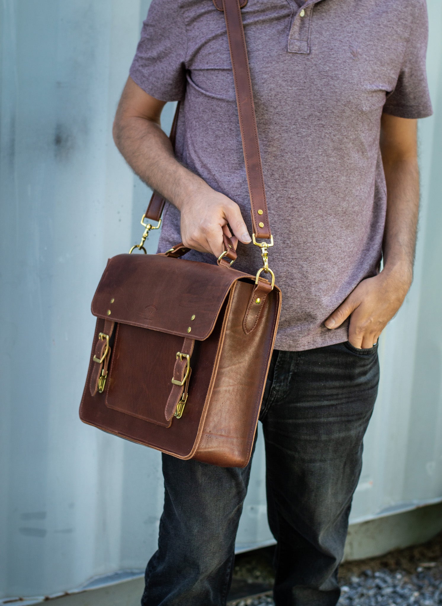 A man holds the convenient grab handle of an Executive Briefcase in whiskey leather. The spacious satchel sitting comfortably on his shoulder. 