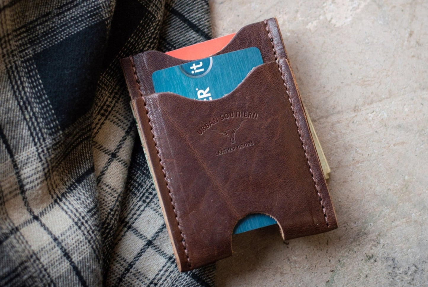 Brown leather wallet with a blue card on a textured surface