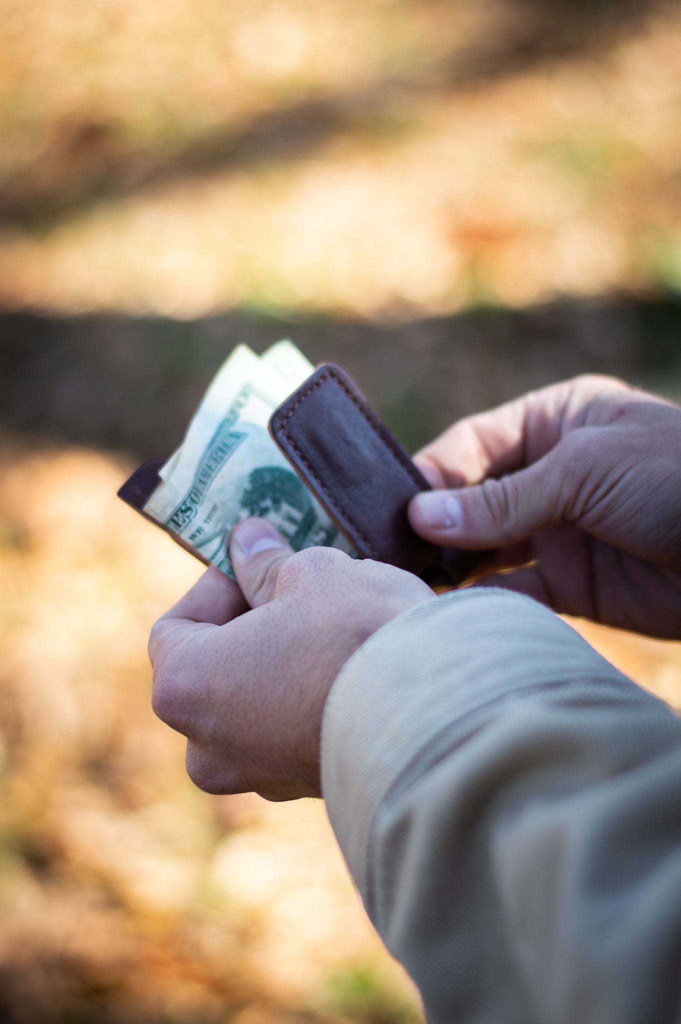 Person holding a wallet removing money from the magnetic clip.